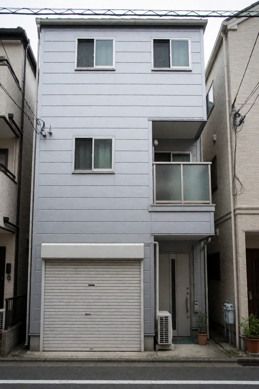 ライトグレーの金属サイディングにビルトインガレージがある狭小3階建て