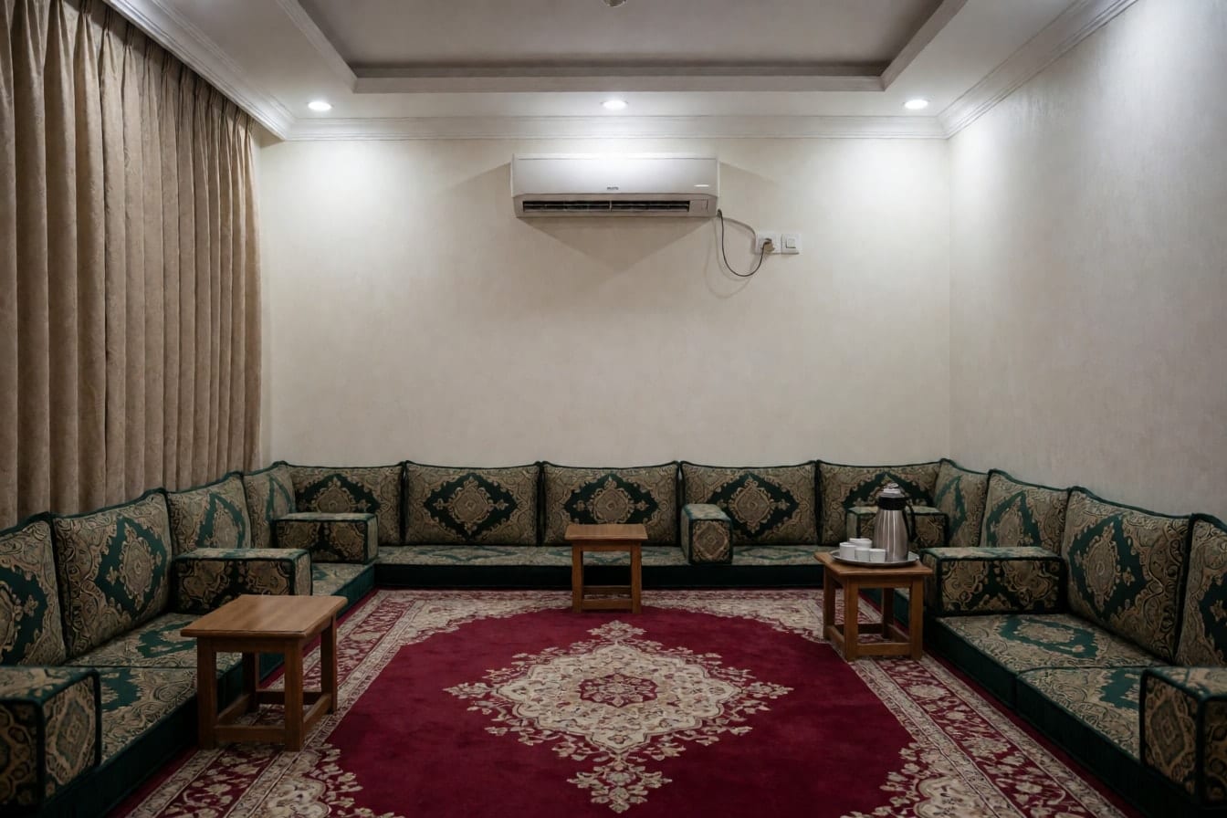 مجلس رجال في فيلا بالرياض بجلسات أرضية خضراء مزخرفة بالذهبي على ثلاثة جدران وسجادة حمراء وترمس قهوة وفناجين على صينية